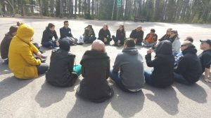Nuori yrittäjä -leirin osallistujat istuvat ulkona ringissä keskustelemassa. Yrittäjyyskurssi maahanmuuttajille syntyi tämän leirin pohjalta.